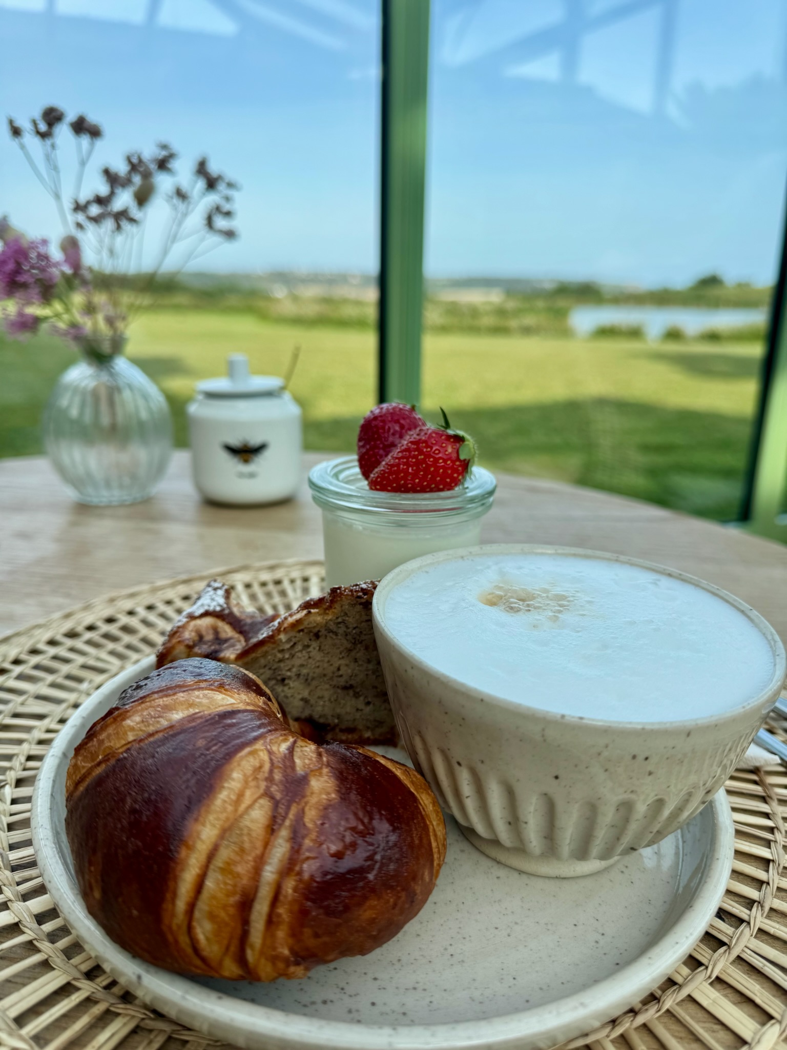 Croissant, cake and cappuccino with a view over the garden